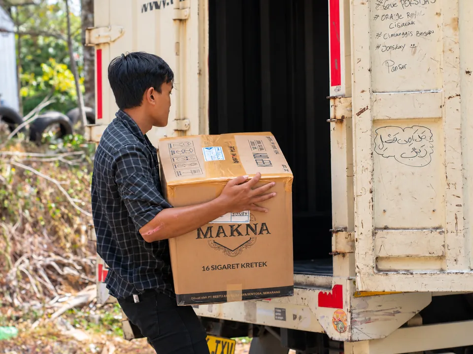 Persiapan Barang ke Kendaraan. Kardus dan barang pesanan dipindahkan menuju kendaraan untuk tahap distribusi.